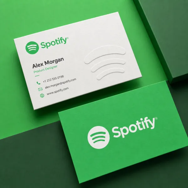 Create a modern business card mockup using the uploaded logo. Two cards are arranged diagonally on a background that automatically matches the brand’s colors. One card features a clean light design, while the other uses the primary brand color. Include simple contact details and realistic textures. Soft studio lighting, slight overhead perspective, clean and professional style.