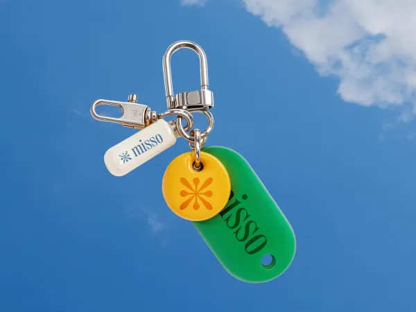 Create a clean, modern carabiner clip assembly mockup. From the primary metal ring, suspend exactly three adaptive tags:
One pill-shaped tag featuring the brand name or slogan in a contrasting color derived from the uploaded brand.
One circular tag prominently displaying the brand’s unique logo icon, with colors adapted from the brand palette.
One large oval tag that automatically adapts its dimensions and color saturation to match the brand’s palette.
The assembly floats in mid-air against a solid background that automatically harmonizes with the uploaded brand’s colors. Use soft, diffused studio lighting to highlight the reflective metal and smooth matte finishes. Composition: clean, minimalist, modern, and high-end, perfectly aligned with the brand’s identity.