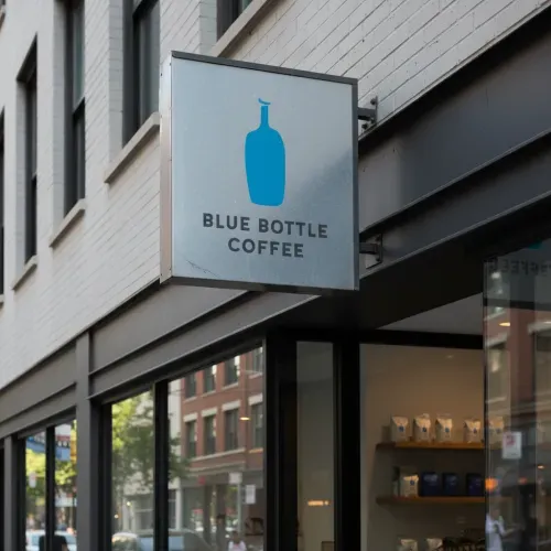 Photorealistic shop sign mockup featuring the uploaded logo, mounted on a storefront. Urban street background, natural daylight, soft shadows and reflections, high detail, professional brand-ready presentation.