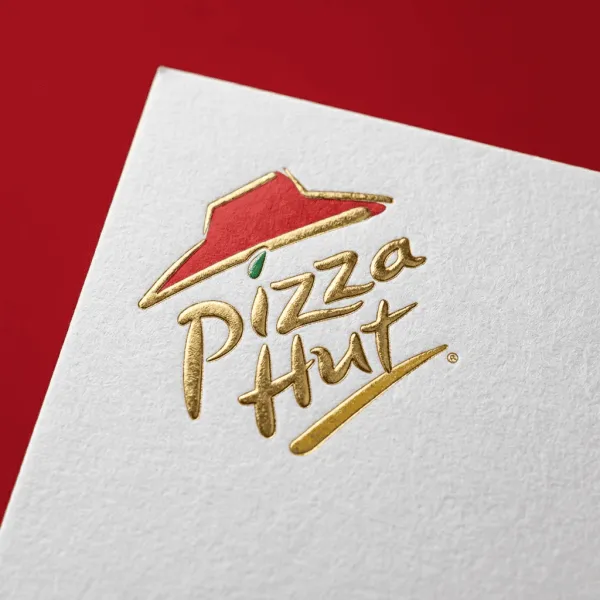 Hyper-realistic close-up of the uploaded logo embossed in gold foil on premium white paper. Showcase fine paper texture and metallic reflections, with just a paper corner visible. Solid brand-color background, sharp focus, and a luxurious, elegant look.